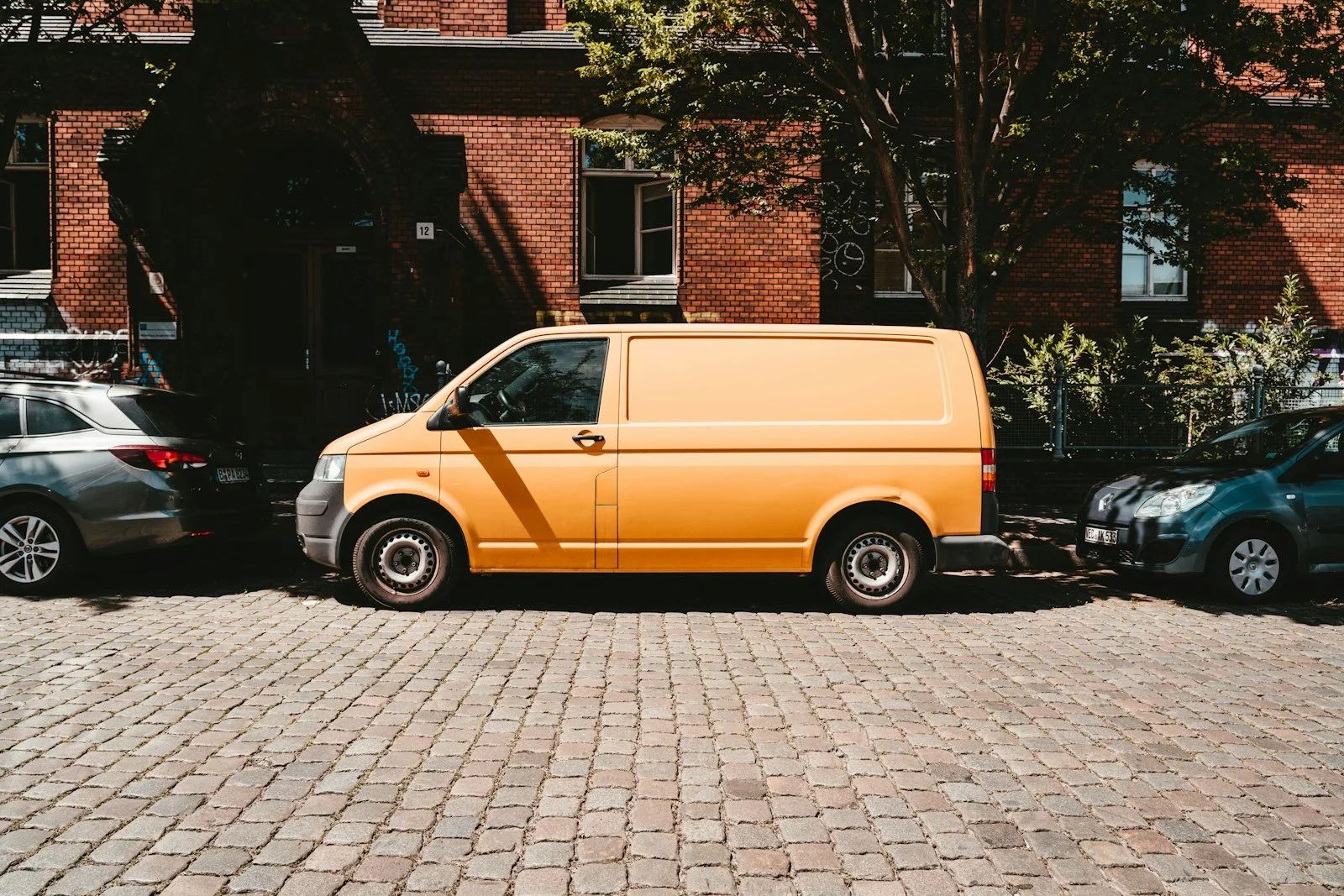 yellow van parked beside brown brick building yellow van parked beside brown brick building
