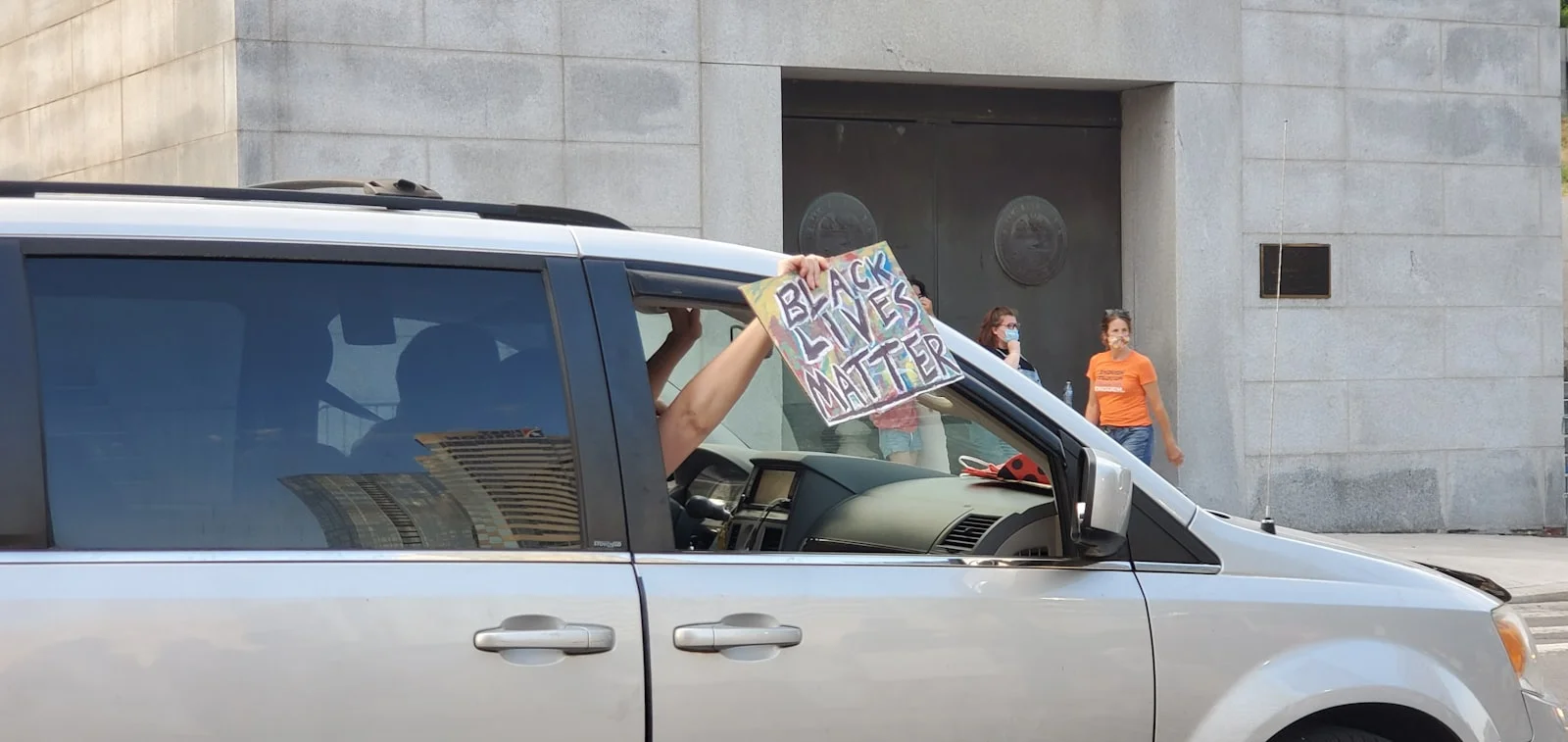 man in white and blue shirt leaning on white car