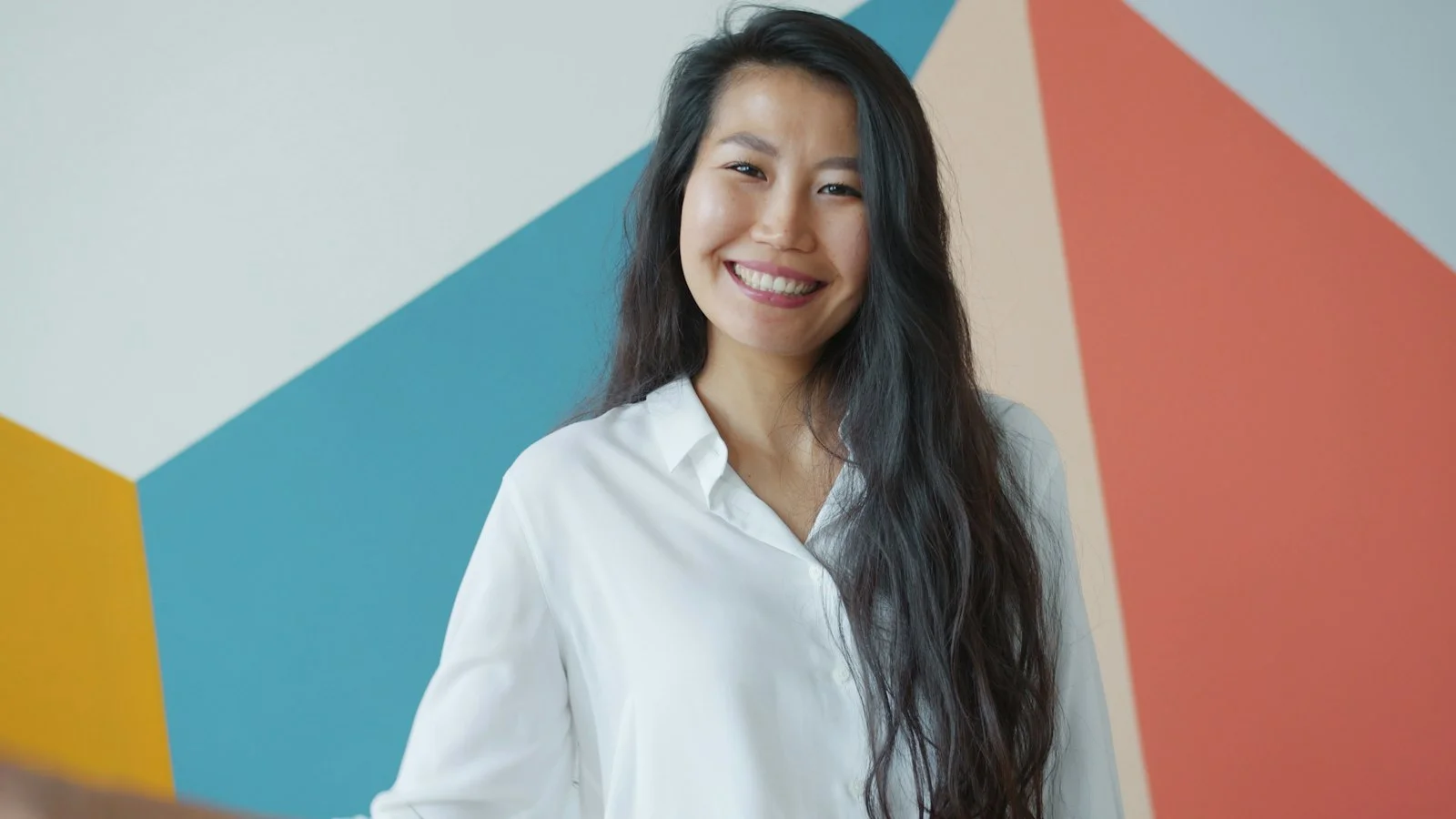 Young woman smiling in front of colorful geometric wall