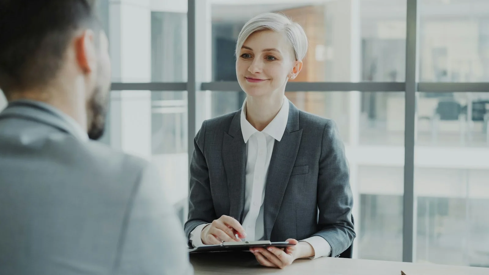 Woman in suit interviews man across table Woman in suit interviews man across table