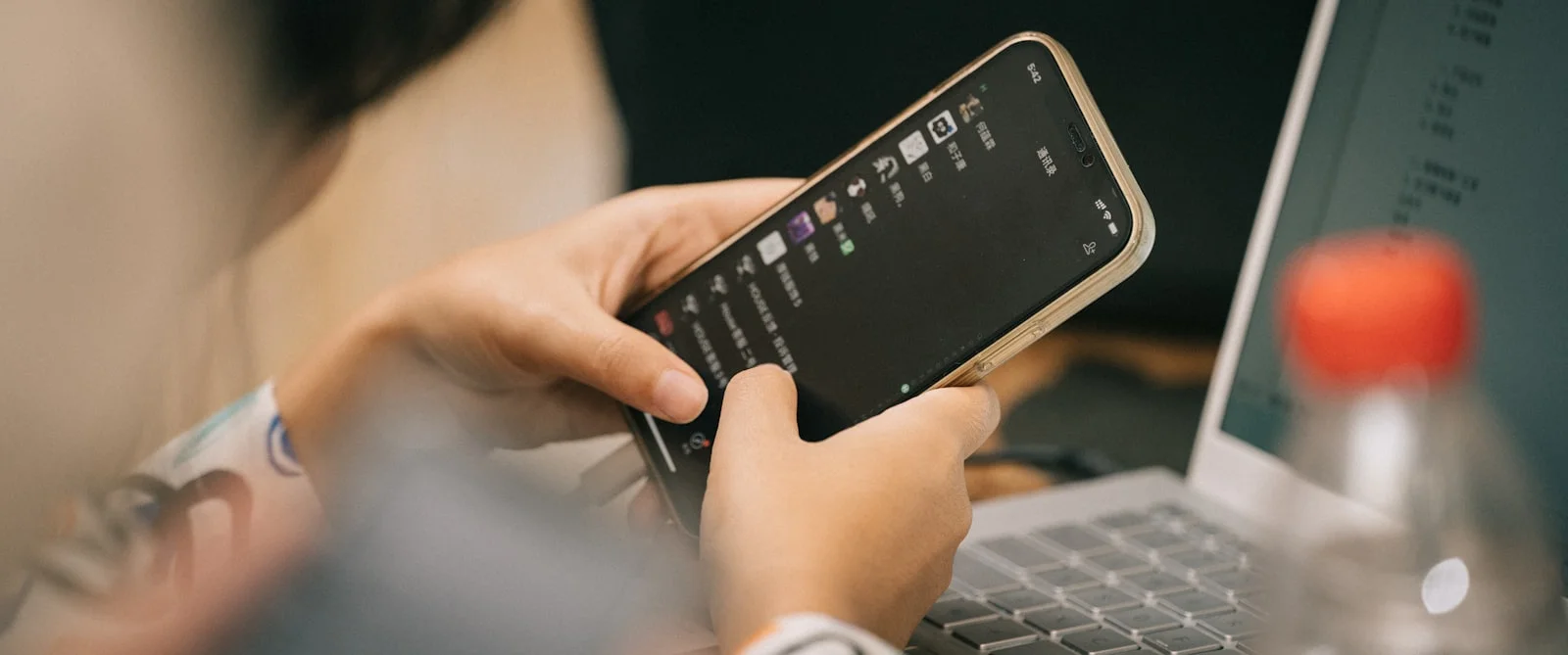 a person using a cell phone while sitting in front of a laptop a person using a cell phone while sitting in front of a laptop